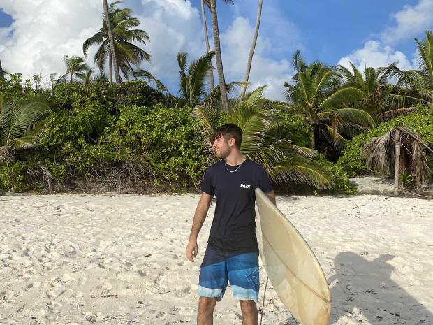 PADI AmbassaDiver Giosue Reale on the beach with a surfboard.