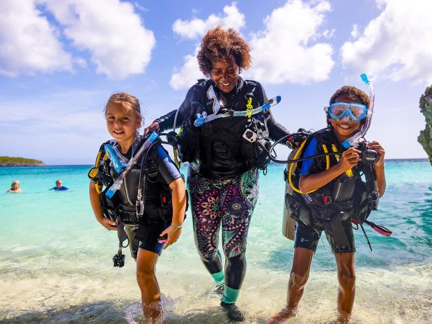 a family walking on the beach with scuba gear